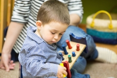 Little child boy playing in kindergarten in Montessori preschool Class.